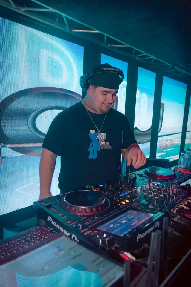 DJ actuando entre pantallas y luz azul